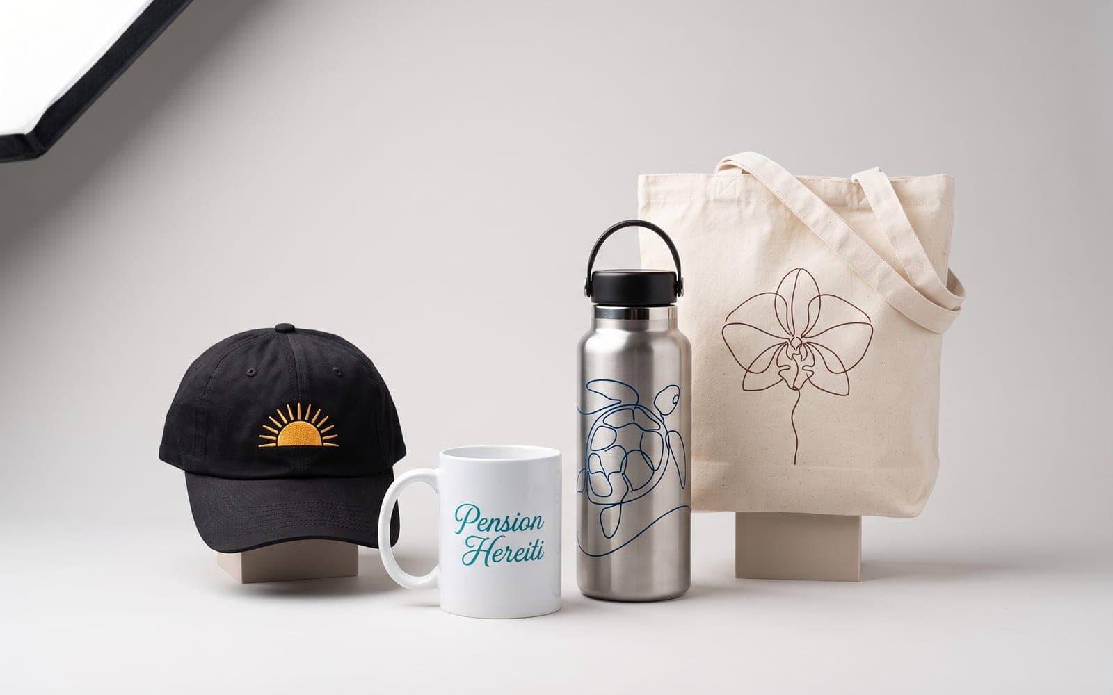 Casquette brodée, mug, gourde et tote bag marqués, réunis en studio.