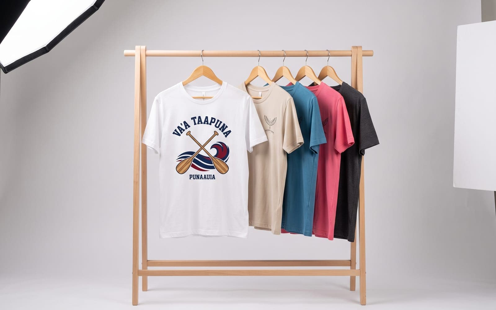Portant de t-shirts imprimés, le premier au marquage d'un club de va'a, coloris variés derrière.